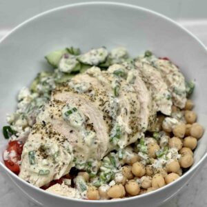 Bowl filled with salad, chicken, chickpeas and dressing